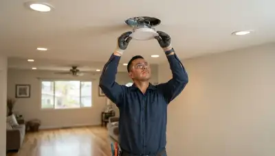 Electrician clips recessed lighting trim flush to ceiling in Long Beach, CA