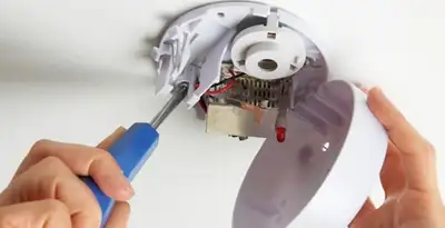 Certified technician wiring smoke detector during installation in Long Beach, CA